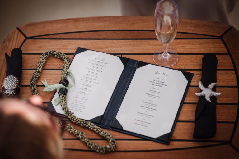 Open menu on table with pearl necklaces, napkins, and a glass of champagne.