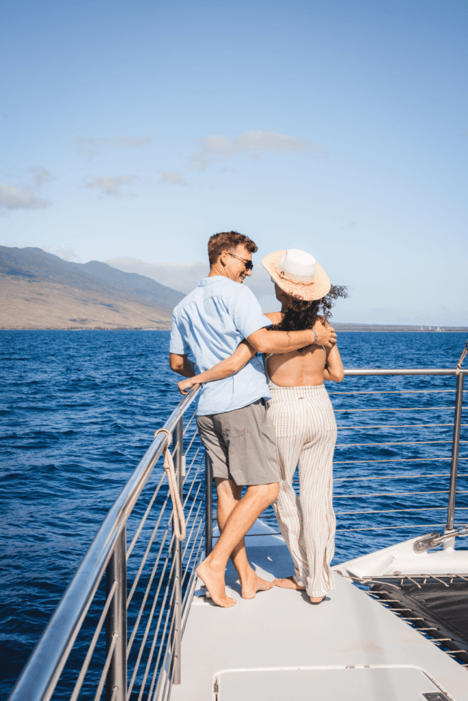 Couple embracing on a boat overlooking the ocean and mountains.