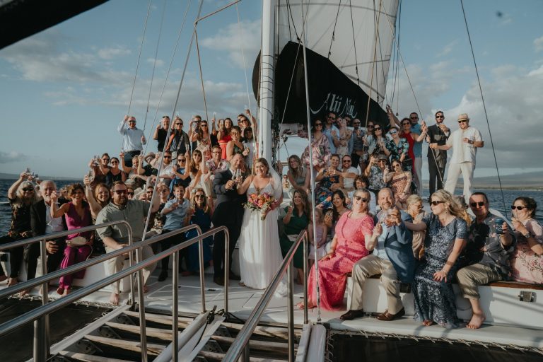 Large group posing on a sailboat with a clear sky.