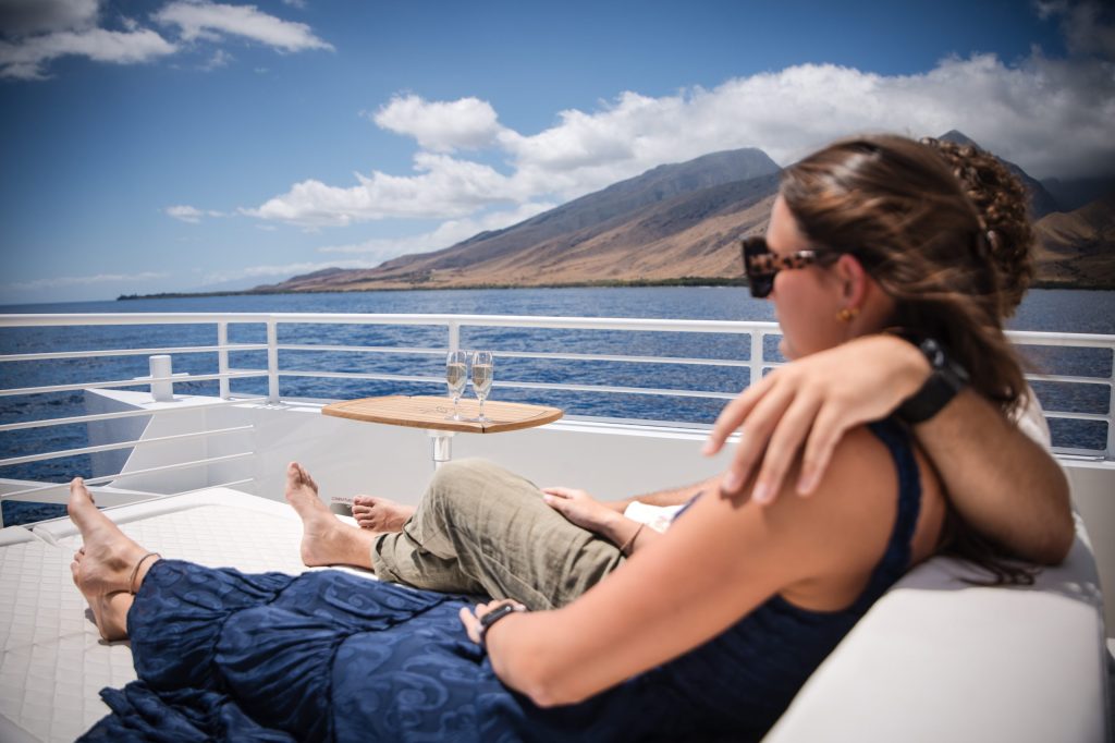 Couple relaxing on a boat with mountain and ocean views.