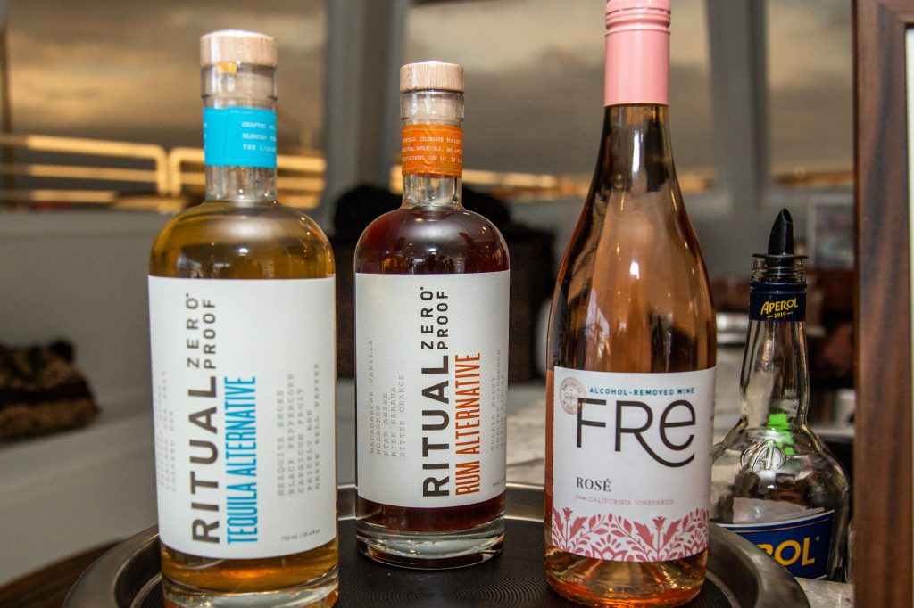 Three bottles of non-alcoholic spirits on a tray indoors.