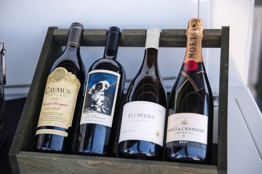 Four wine bottles in a wooden rack, two red and two white.
