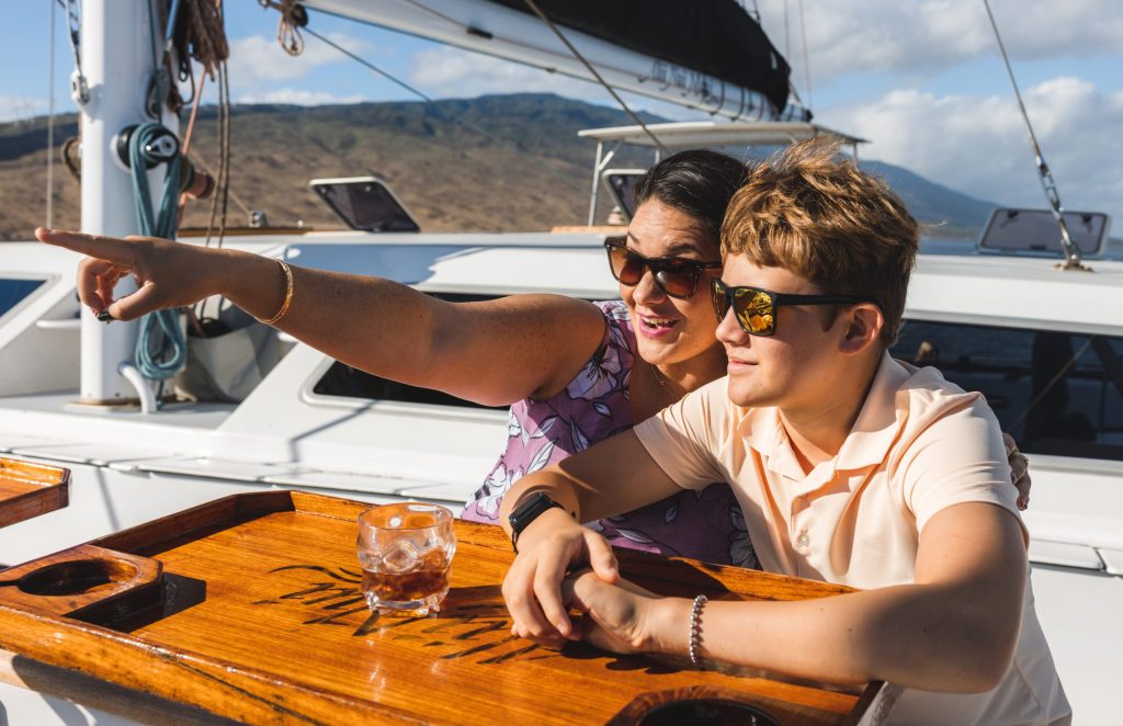 Two people on a boat, one pointing, both wearing sunglasses.