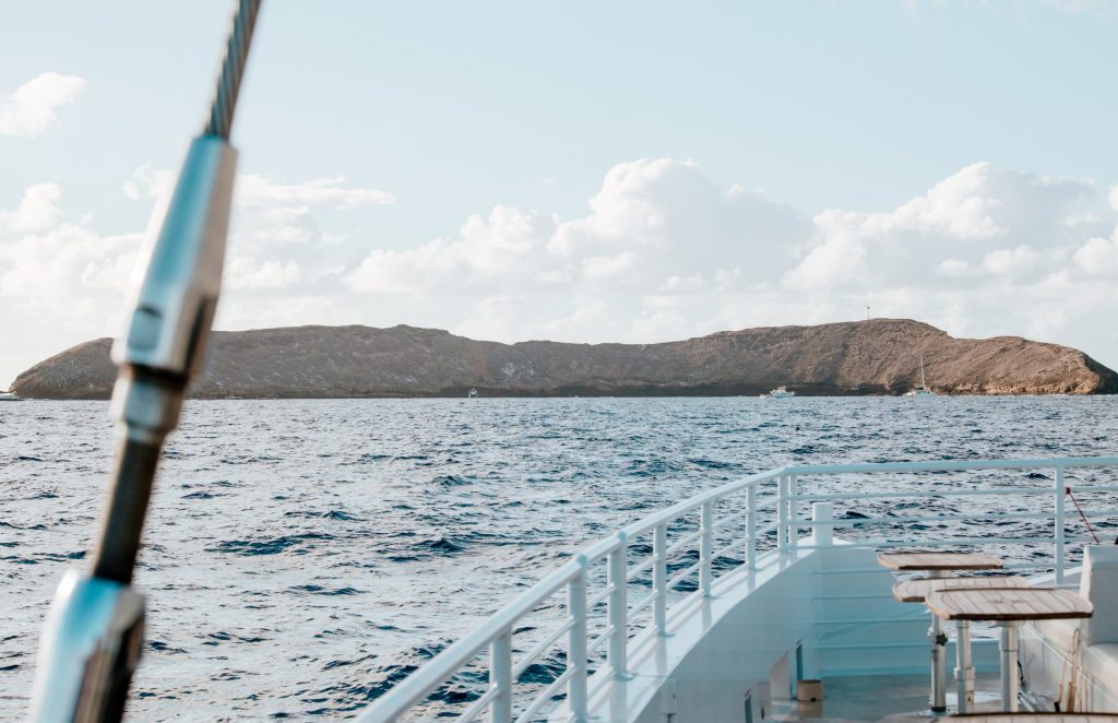Boat approaching rocky island on a sunny day with scattered clouds.