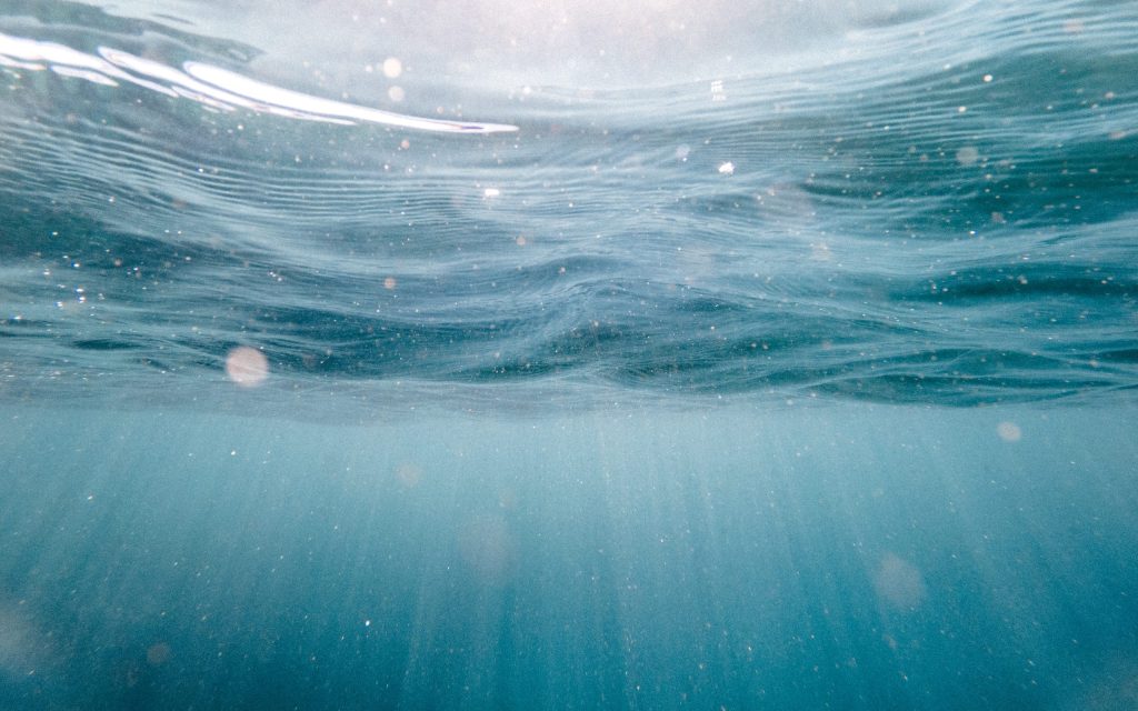 Underwater view with sunlight filtering through blue water.