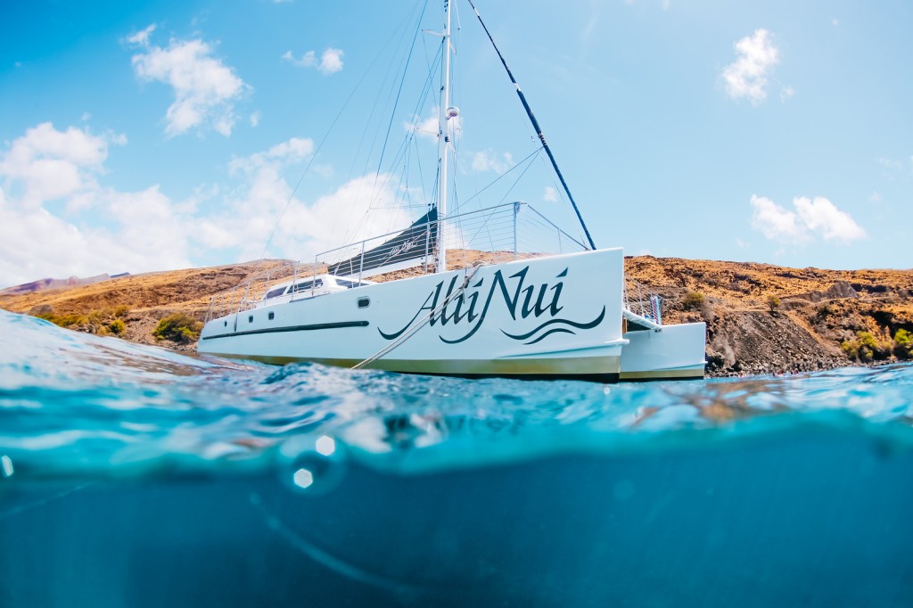Catamaran 'Alii Nui' with blue ocean and cloudy sky.