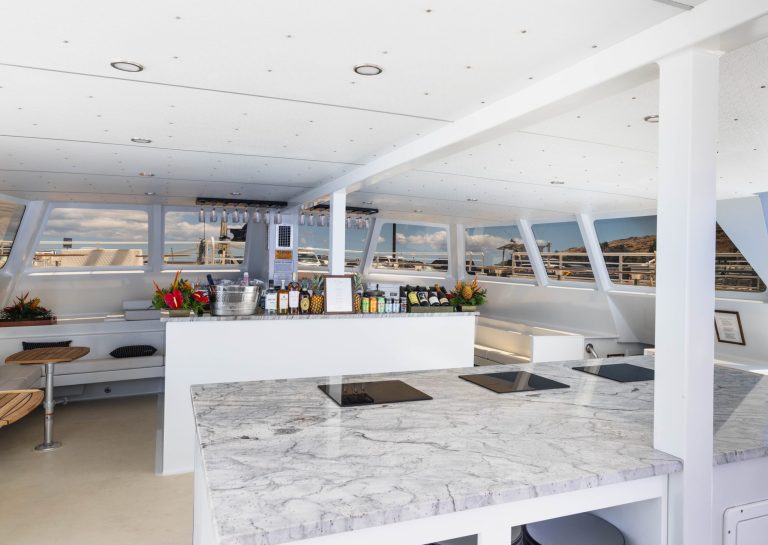 Modern boat interior with marble counters, bar, and large windows.