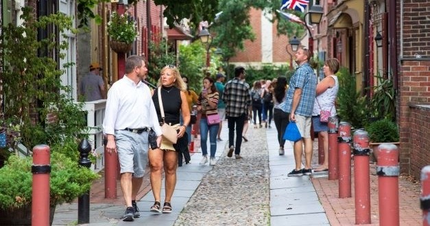 People walking on a cobblestone street with buildings and a UK flag.