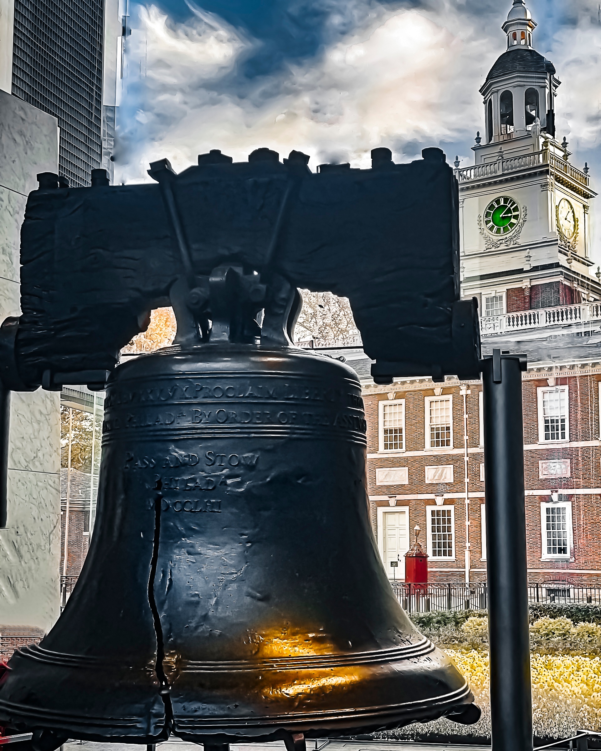The Liberty Bell with Independence Hall in the background on a cloudy day.
