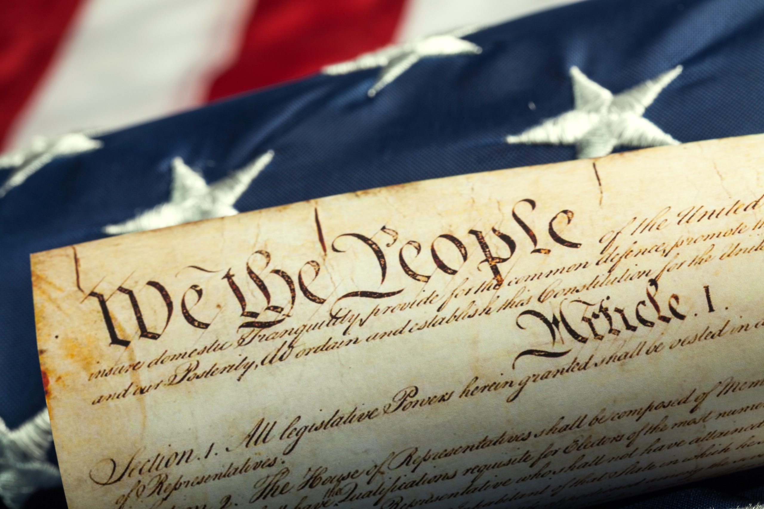 Close-up of the U.S. Constitution on a background of an American flag.