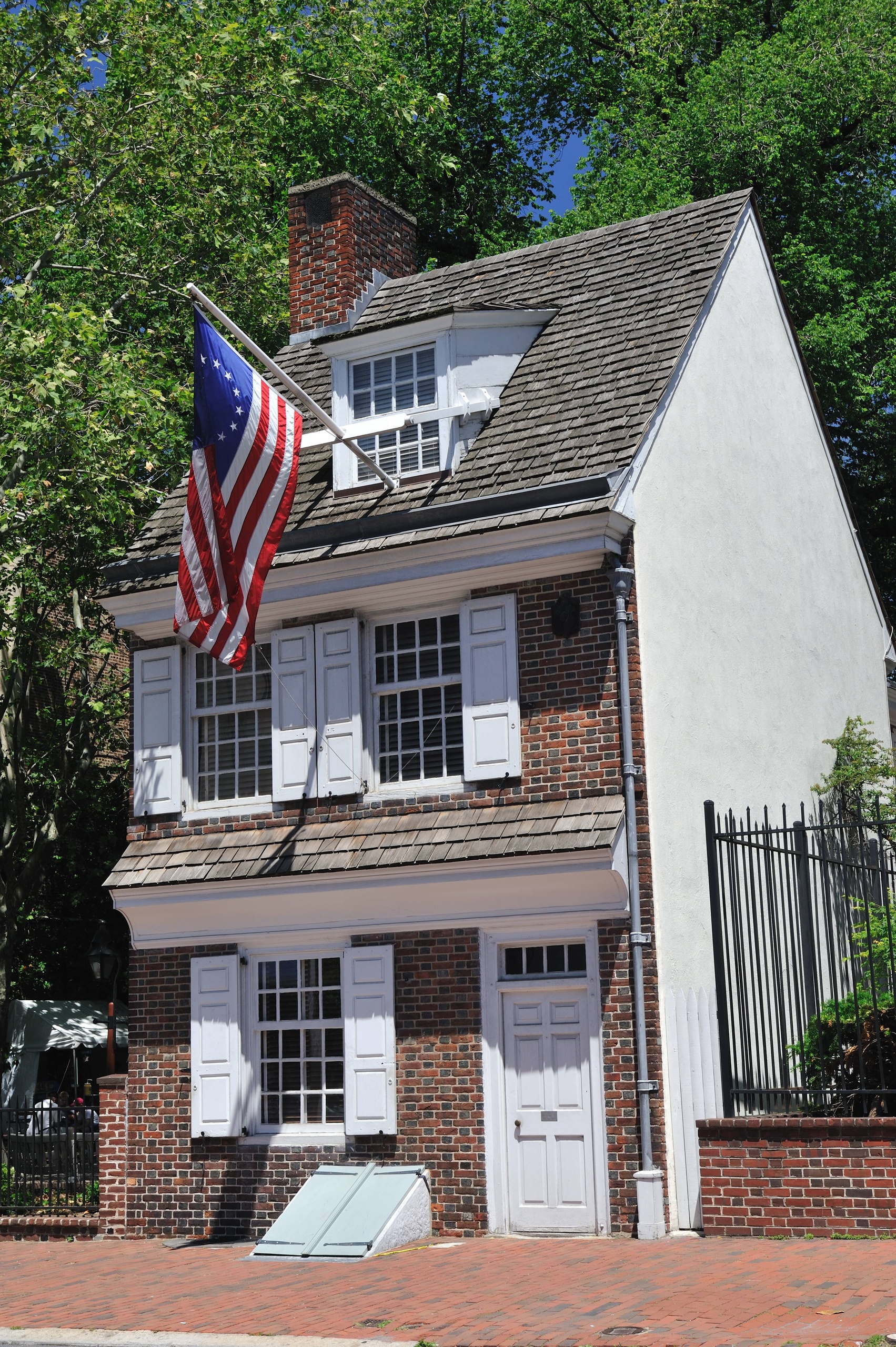 Historic brick house with an American flag and white shutters.