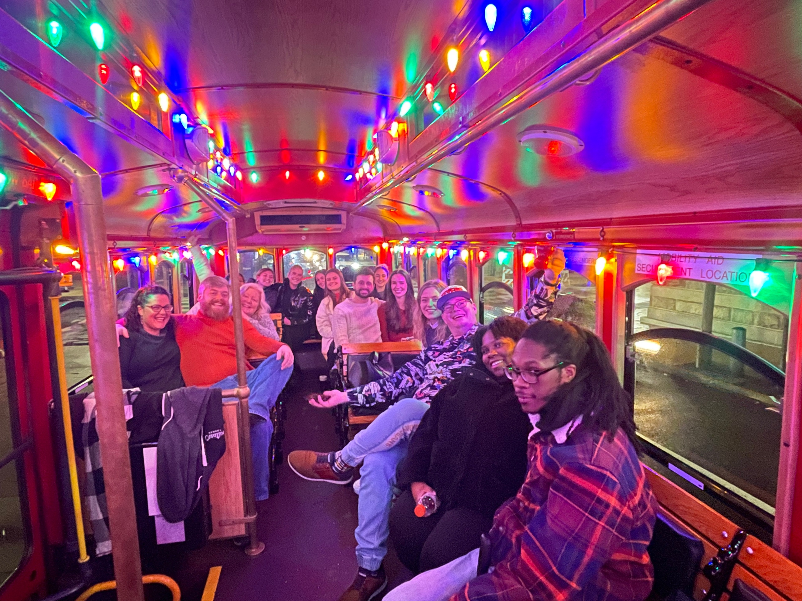 Group of people inside a colorful, decorated bus with bright lights.
