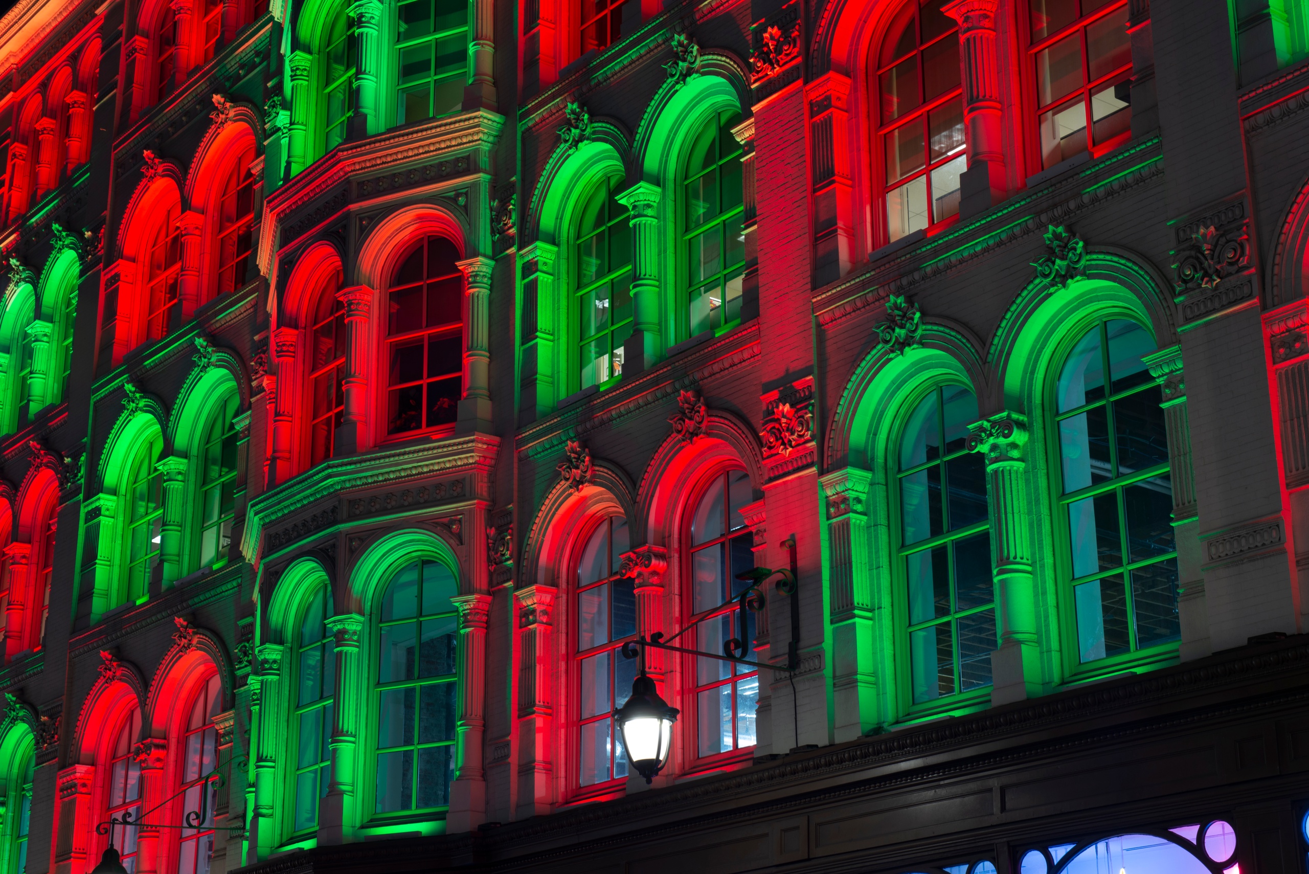 Building facade lit in red and green lights, with arched windows.