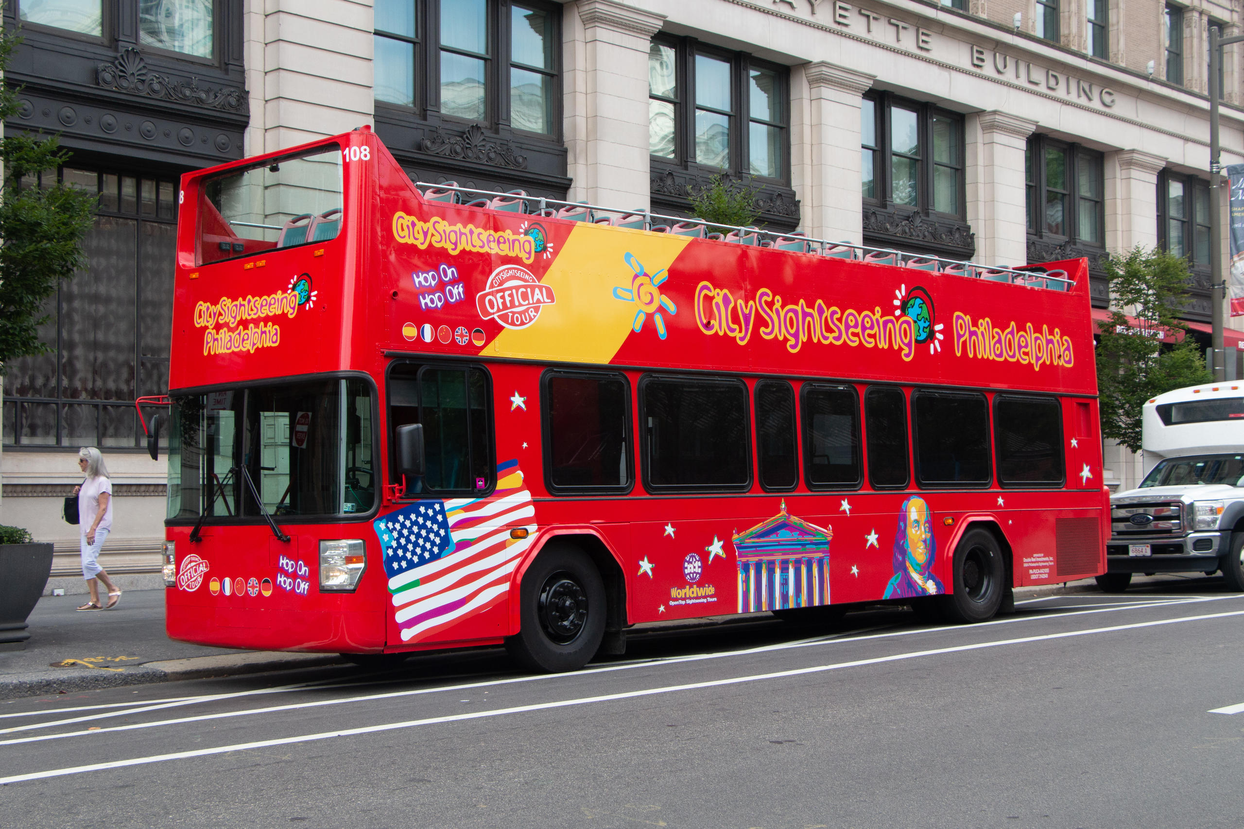 Red double-decker sightseeing bus parked on city street.