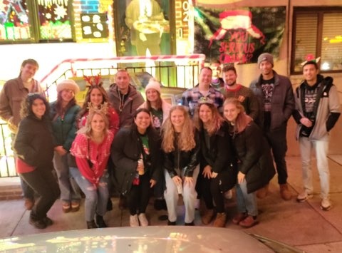 Group of people in festive attire posing on a sidewalk.