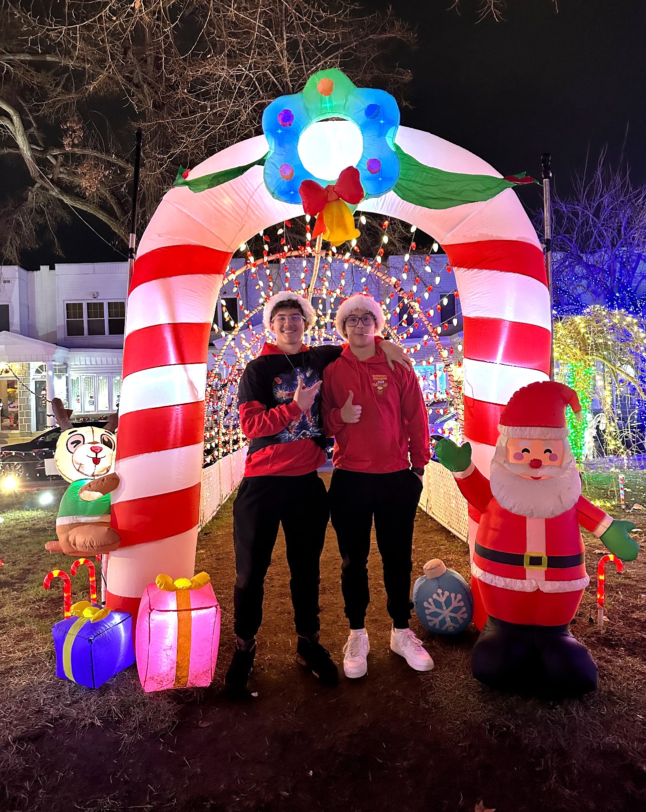 Two people under a lighted candy cane arch with Christmas decorations.