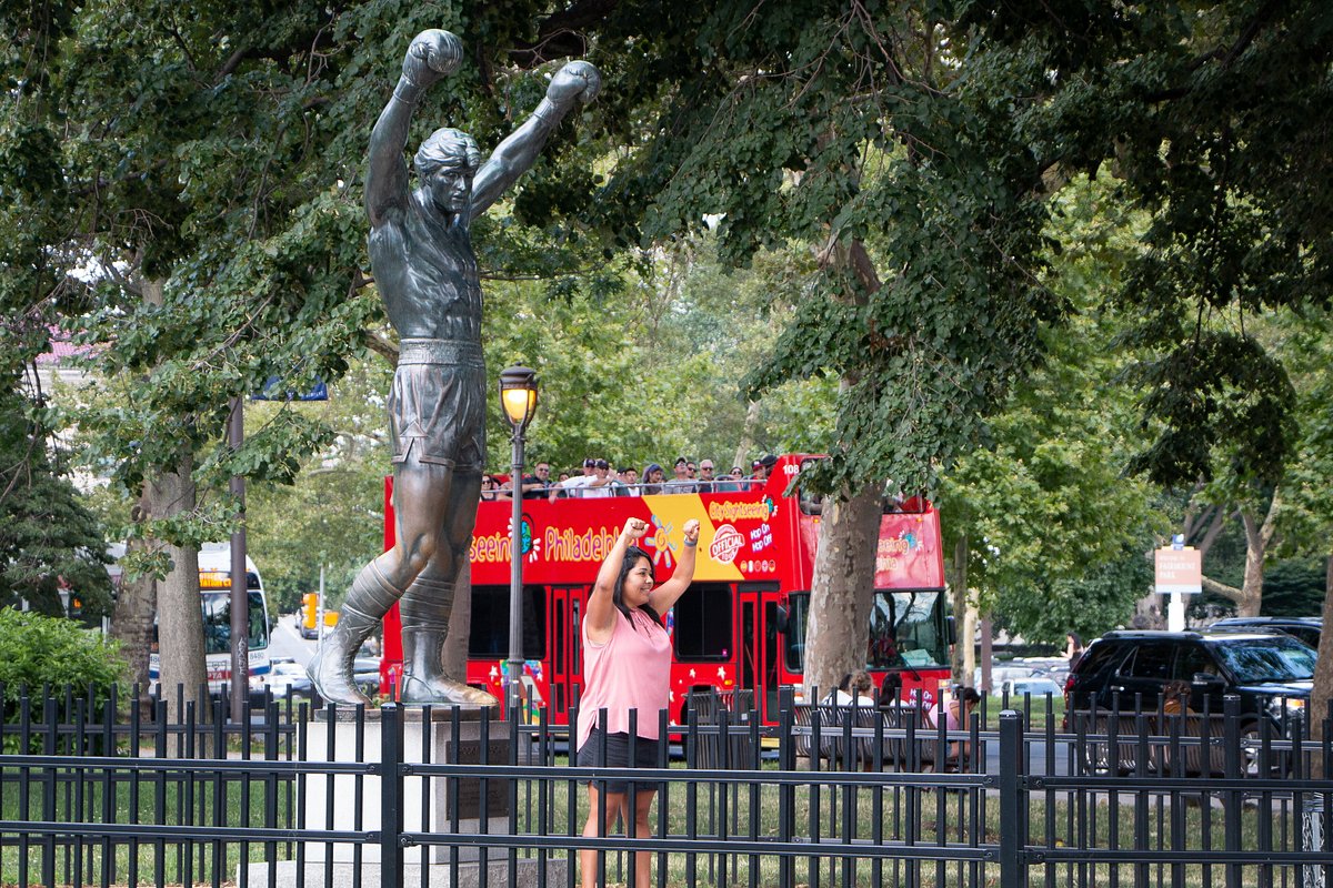 Person taking a selfie with a statue of a boxer in a park.