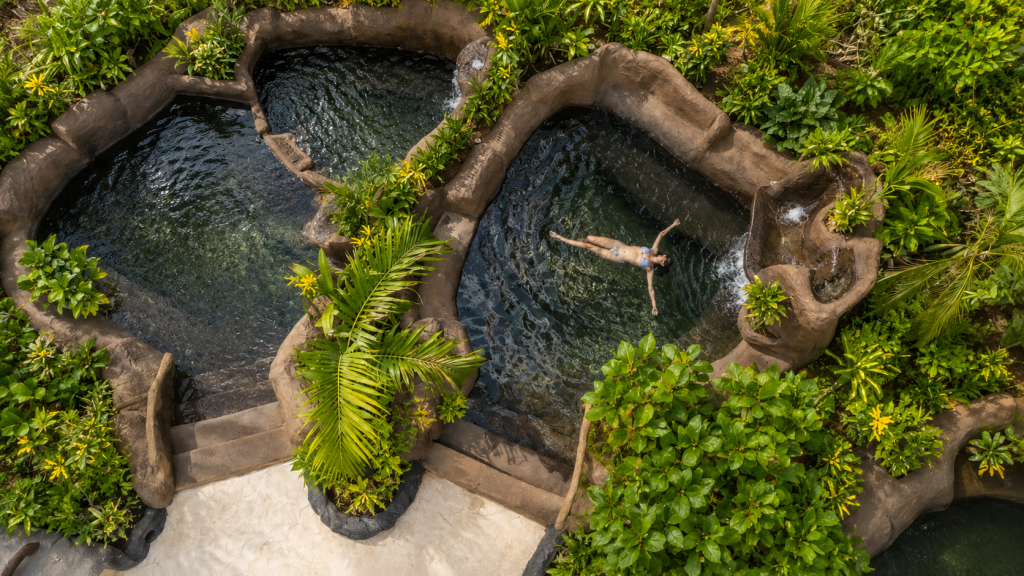 Person floats in a natural pool surrounded by lush greenery.