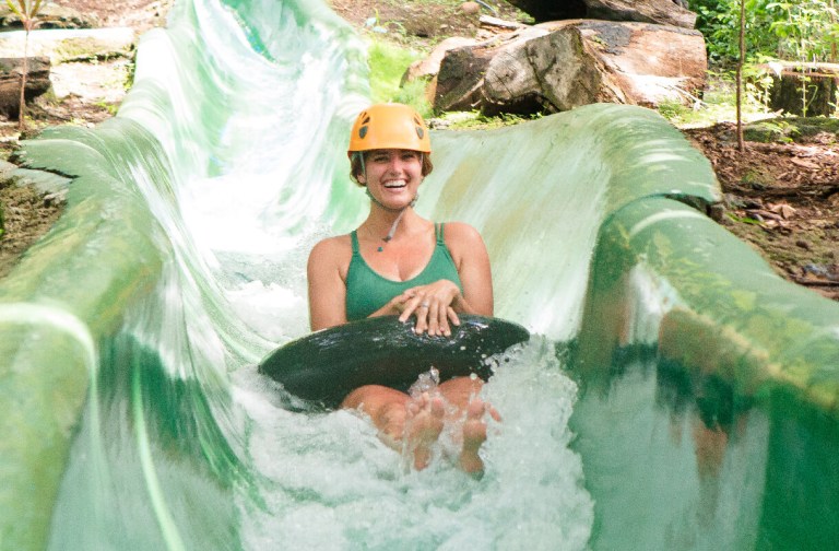vandara-activities-waterslide Person in helmet tubing down a water slide surrounded by greenery.